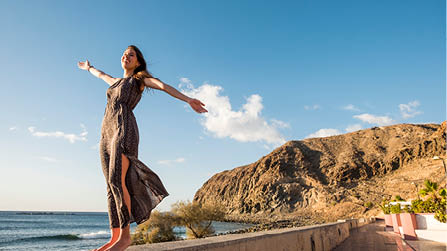 Young nice woman enjoy her freedom opening arms  Independent life and great feel with the world  Embrace all with satisfaction  Tenerife soul 